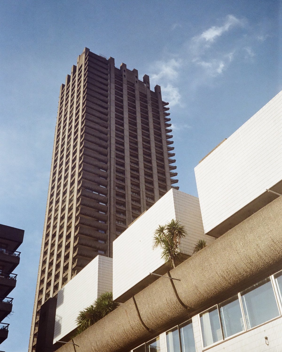 Film photograph looking up at a Barbican tower block against a blue sky in London