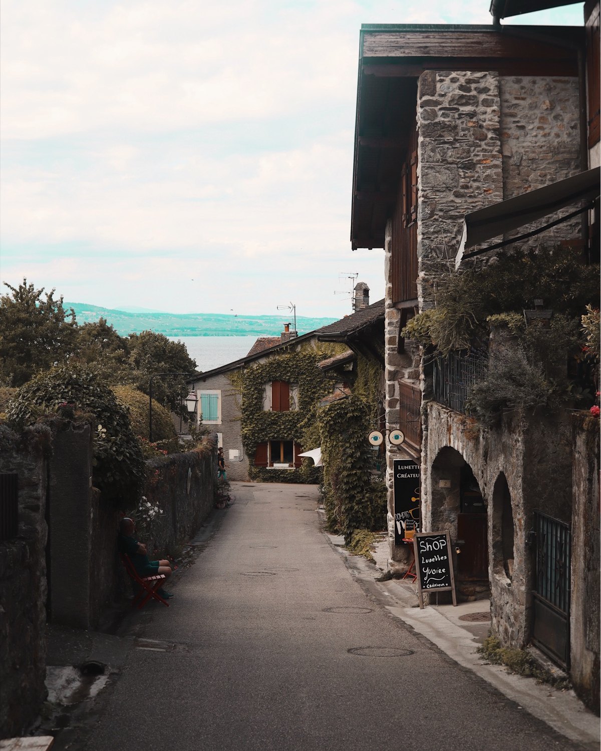 A narrow stone street in the medieval village of Yvoire with Lake Geneva visible in the distance